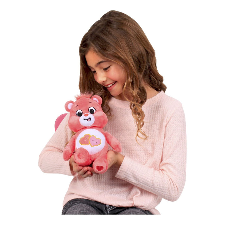 Girl smiling and holding pink plush, love a lot care bear